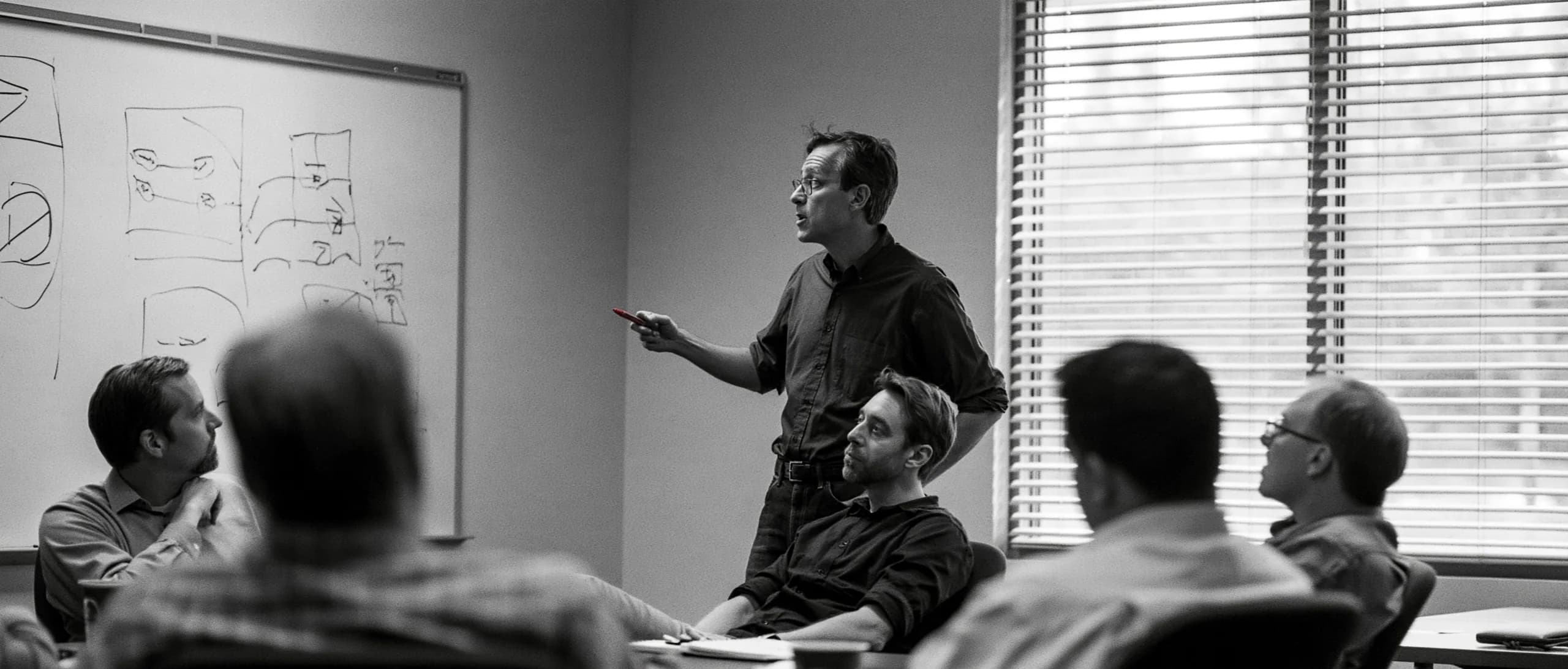 An interim manager working through a plan at a whiteboard with a client's management team